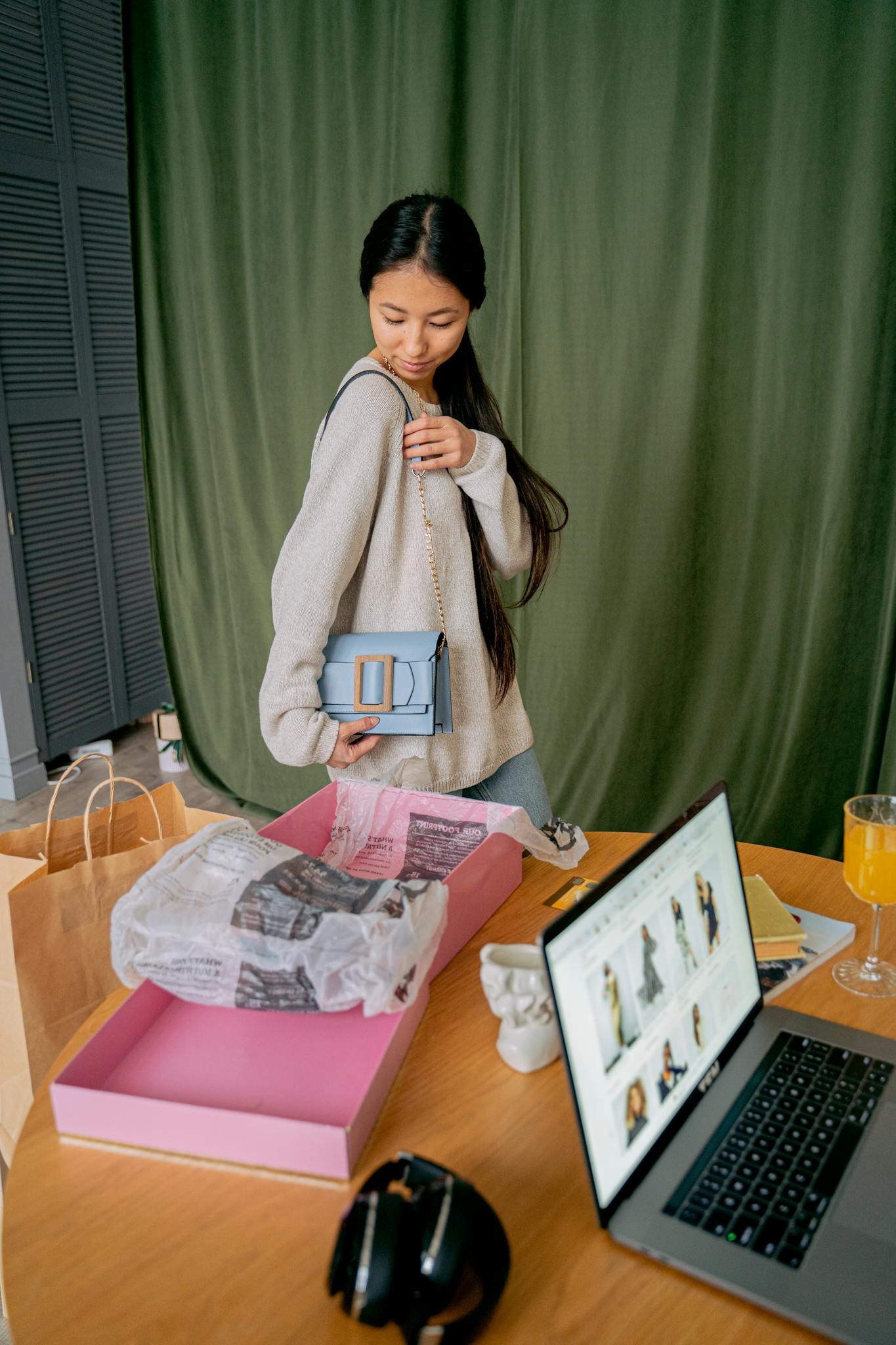 A young woman delights in unboxing her new handbag while shopping online at home.