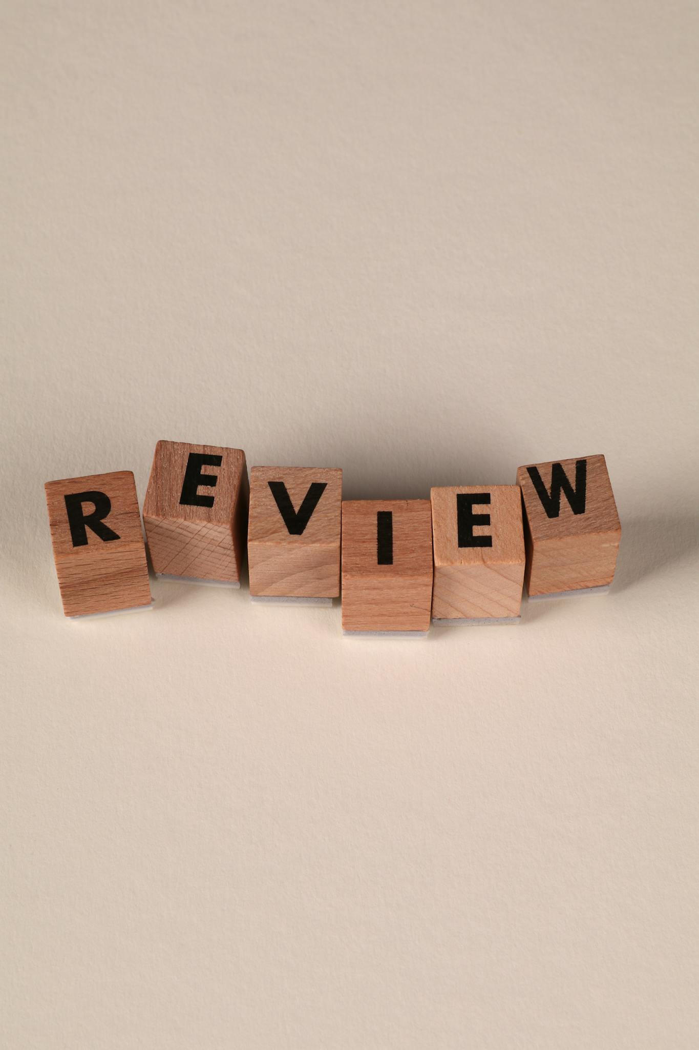 Wooden blocks spelling 'review' on a neutral background, perfect for educational or business concepts.